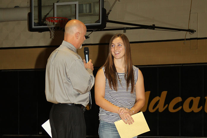 Senior Morgan Knobloch receives All-State Journalism staff award from Principal Vance Morris at the first day of school assembly.