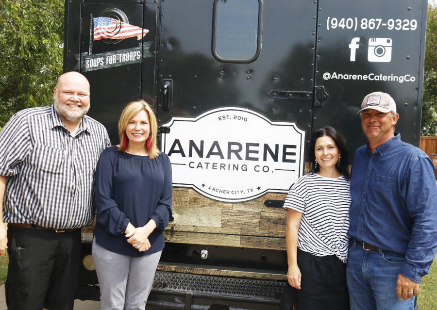The owners of the food truck pose with their company logo