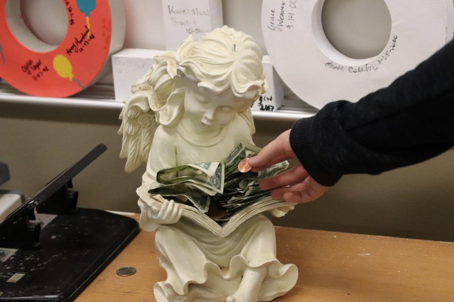 A student places a penny on the angel for good luck.