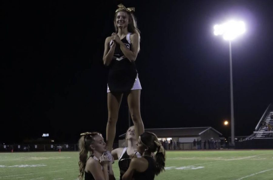 Sophomore Adelyn Harvey and juniors Abby Havens, Katelyn Casillas, and Jaycee Holley perform a stunt at the game against the Quanah Indians.