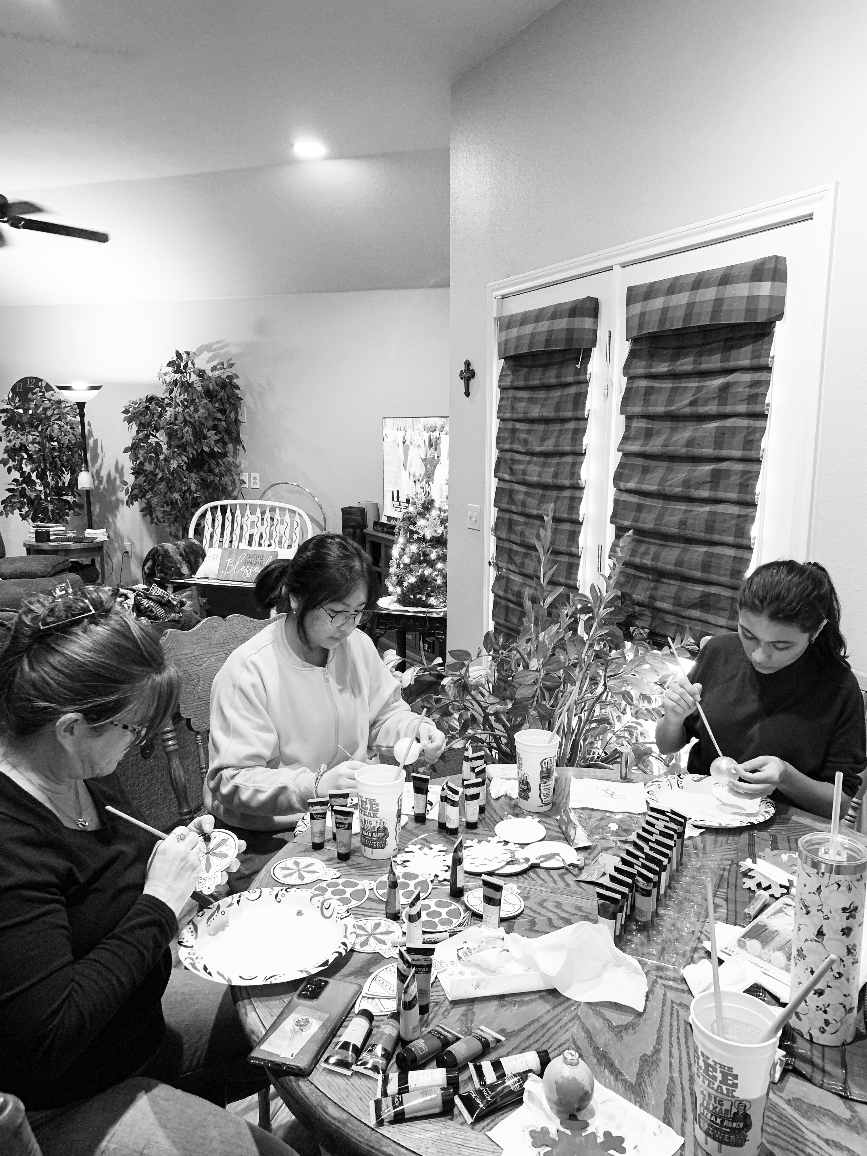 Exchange students Chenah Peertanyanonth and Oisha Halimova decorate Christmas ornaments with their host mother, Carrie Vandiver. 