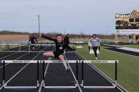 Seventh grader Chevy Wallace jumps over hurdles in race