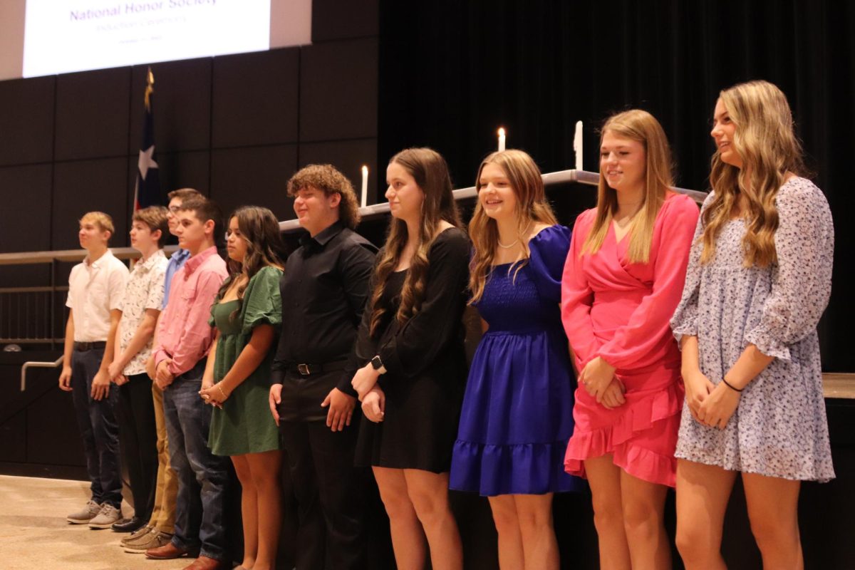 The new National Honor Society inductees recite the pledge and wait to be pinned. 